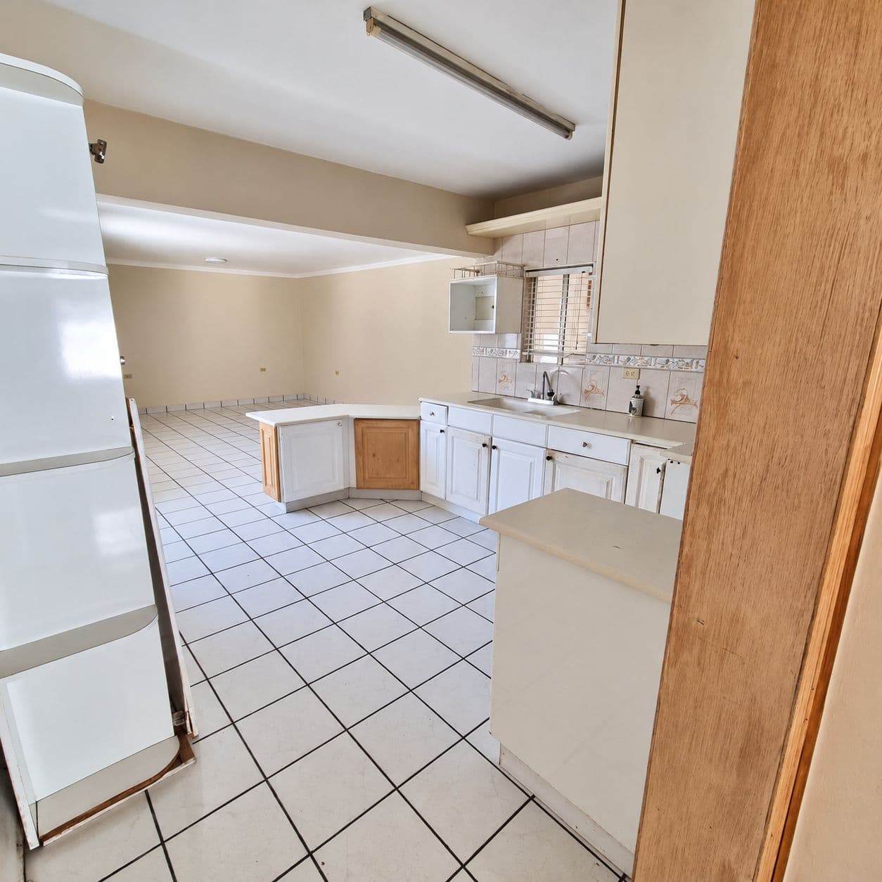 Cocina con gabinetes, tarja y conexión al área de comedor.